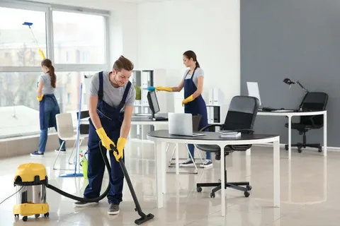 A team of commercial cleaning specialists from Eco Techno Clean cleaning an office, with a male cleaner vacuuming the floor and two female cleaners dusting desks and windows in Toronto.