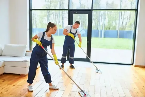 Two Eco Techno Clean professionals mopping a hardwood floor in a bright Toronto home with large windows, demonstrating efficient house cleaning.